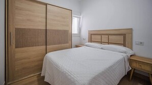 Une chambre à coucher avec un lit, une armoire en bois, des tables de chevet et une fenêtre.