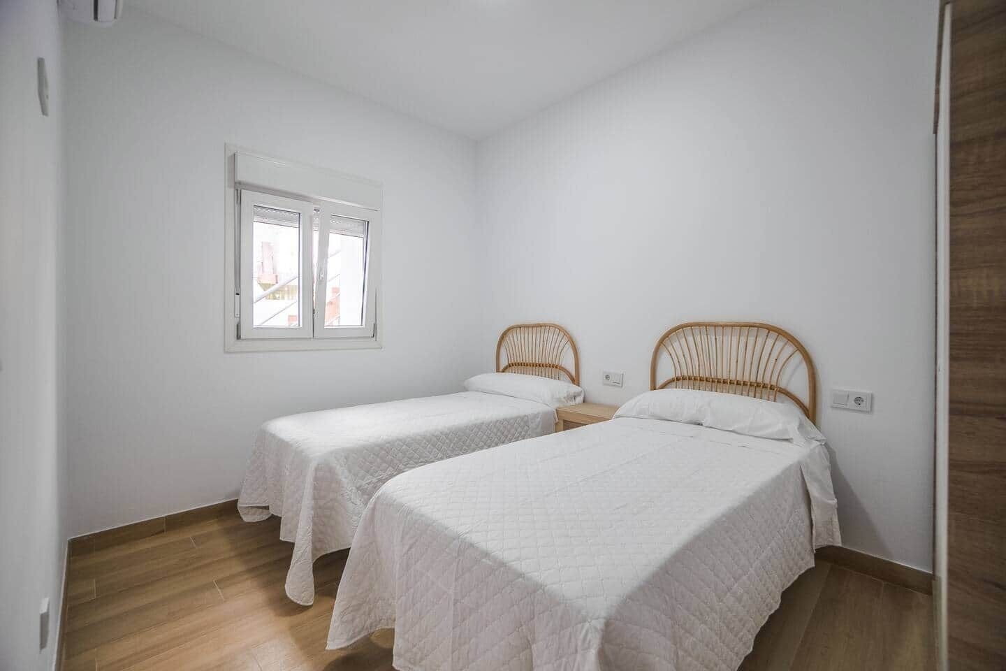 Una habitació amb dos llits individuals, una finestra i una porta.