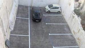 Un espace de stationnement avec des emplacements délimités et deux voitures garées.