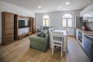 A modern living room with a TV, sofa, dining table, and kitchen area. - Downtown Apartment, Patio Cuarenta 2A (Algeciras)