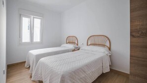 Een kamer met twee eenpersoonsbedden, een raam en een houten vloer.