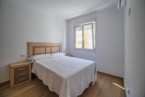 Ein Schlafzimmer mit einem Bett, einem Nachttisch aus Holz und einem Fenster.