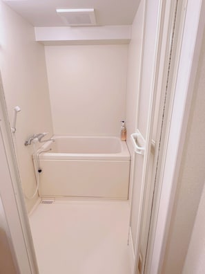 Une salle de bain blanche avec une baignoire, une douche et un sèche-mains.