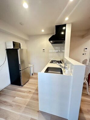 A modern kitchen with a built-in stove, a microwave, and a refrigerator. - sannritsu (Tokyo)