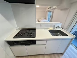 Une petite cuisine équipée d’une cuisinière à gaz, d’un évier et d’un lave-vaisselle.