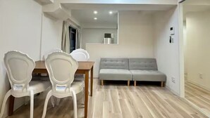 En kompakt opholdsstue med spisebord, to stole, sofa og spejl.