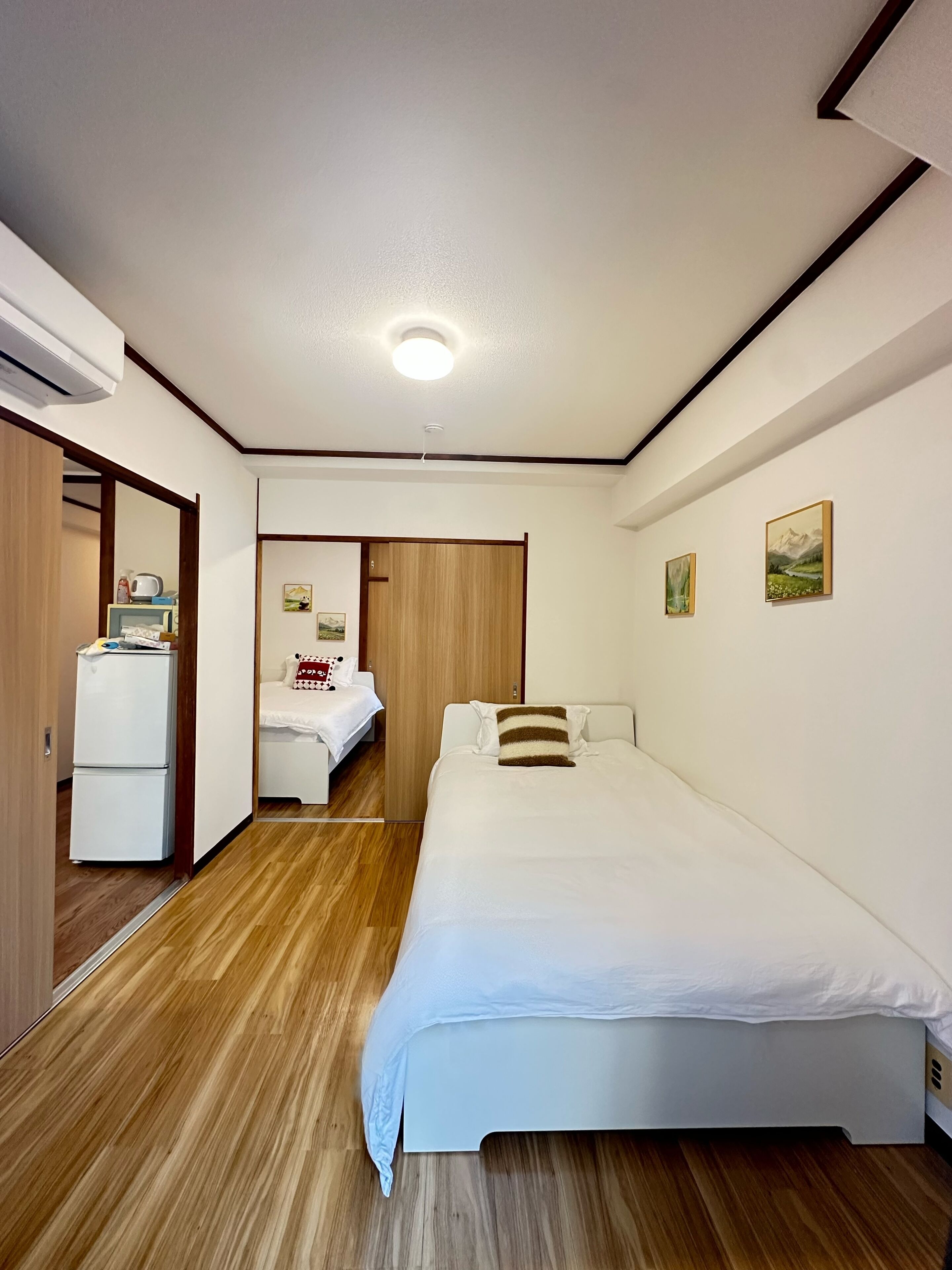 Une chambre comprenant un lit, une armoire, un petit coin cuisine et une porte donnant sur une autre pièce.