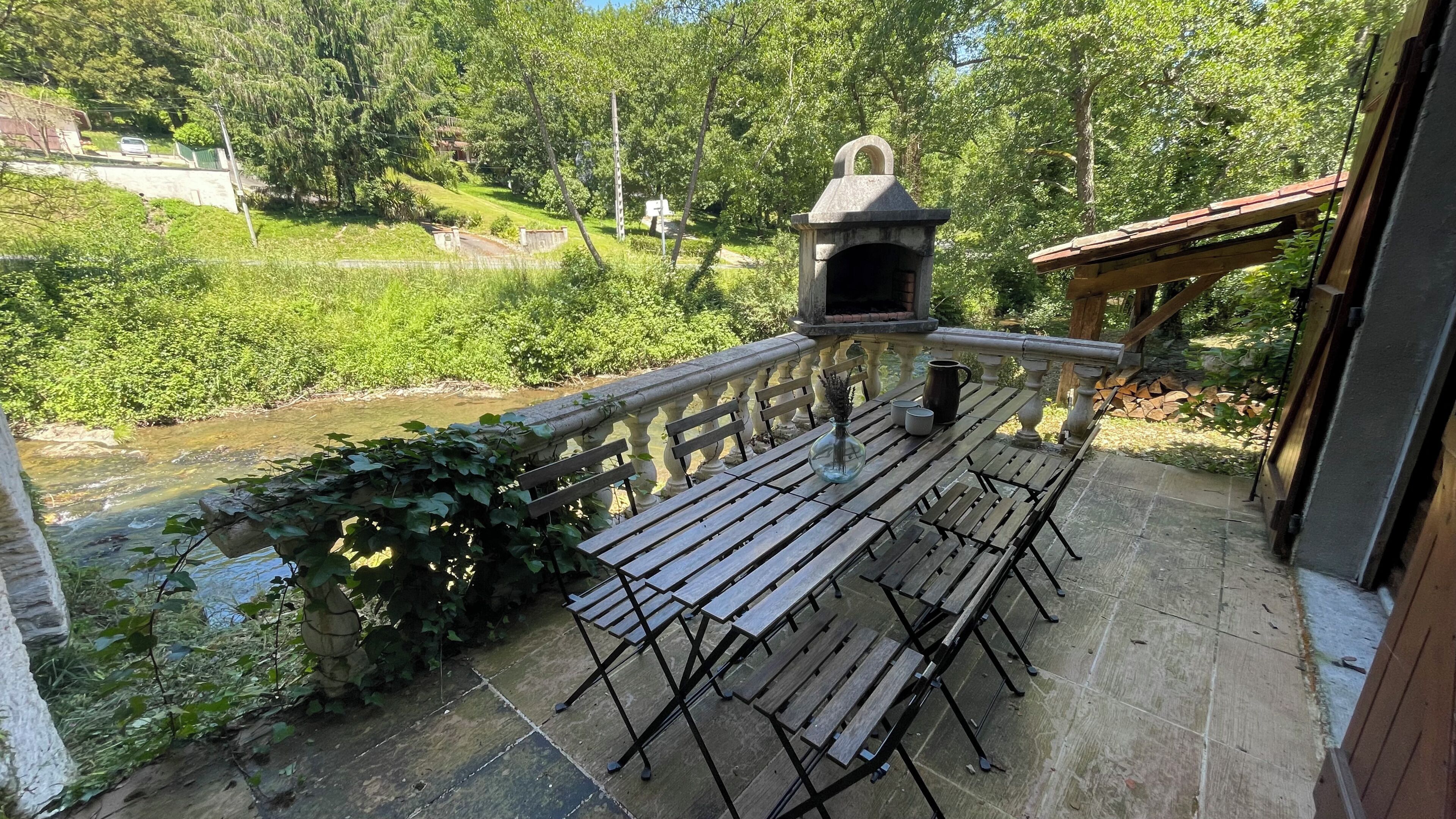 A patio with wooden benches and a stone wall overlooking a river.
