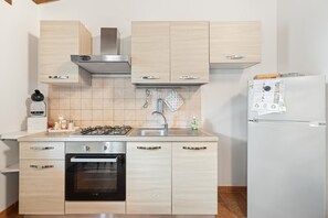 A modern kitchen with light wood cabinets, stainless steel appliances, and a built-in oven.