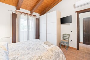 Un dormitorio con cama, una silla, televisor y armario.