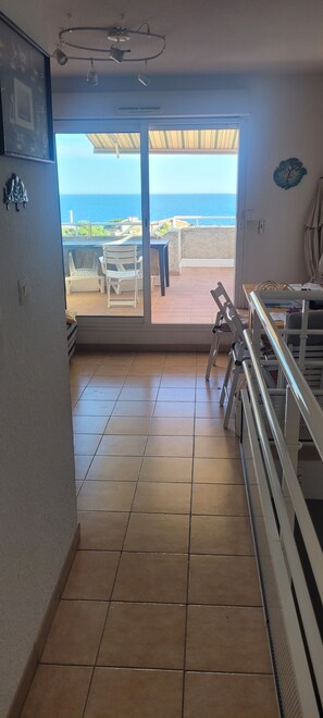Ein Zimmer mit Meerblick, ein Balkon mit Stühlen und eine Essecke mit Tisch und Stühlen.