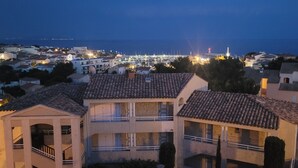 Uma cidade costeira ao entardecer, com edifícios que exibem telhados de terracota e varandas.