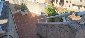 Eine Terrasse mit Fliesenboden, Kübelpflanzen und einem weißen Geländer.