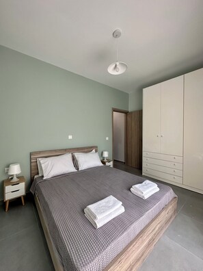 A bedroom with a bed, nightstands, a wardrobe, and a ceiling light. - Zouf House Luxury Stay with Jacuzzi (Agios Panteleimon)