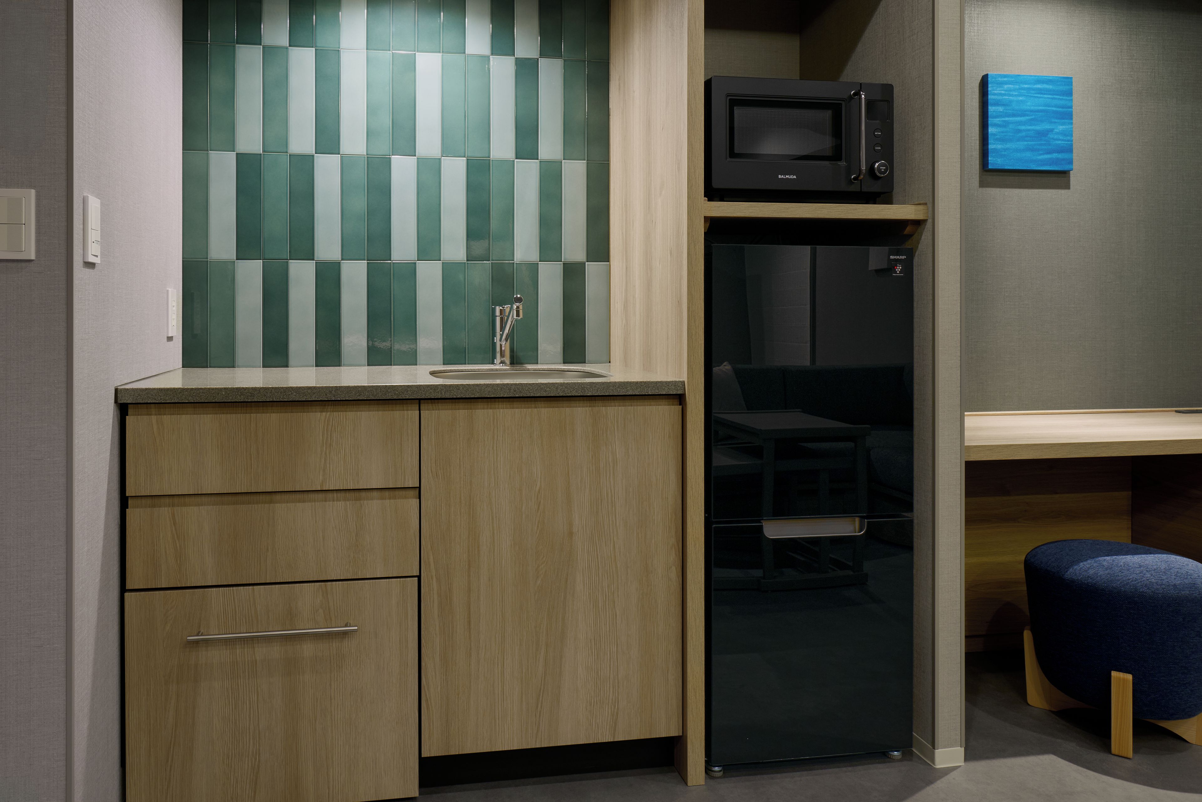 Uma kitchenette compacta com micro-ondas, pia e armário de madeira.