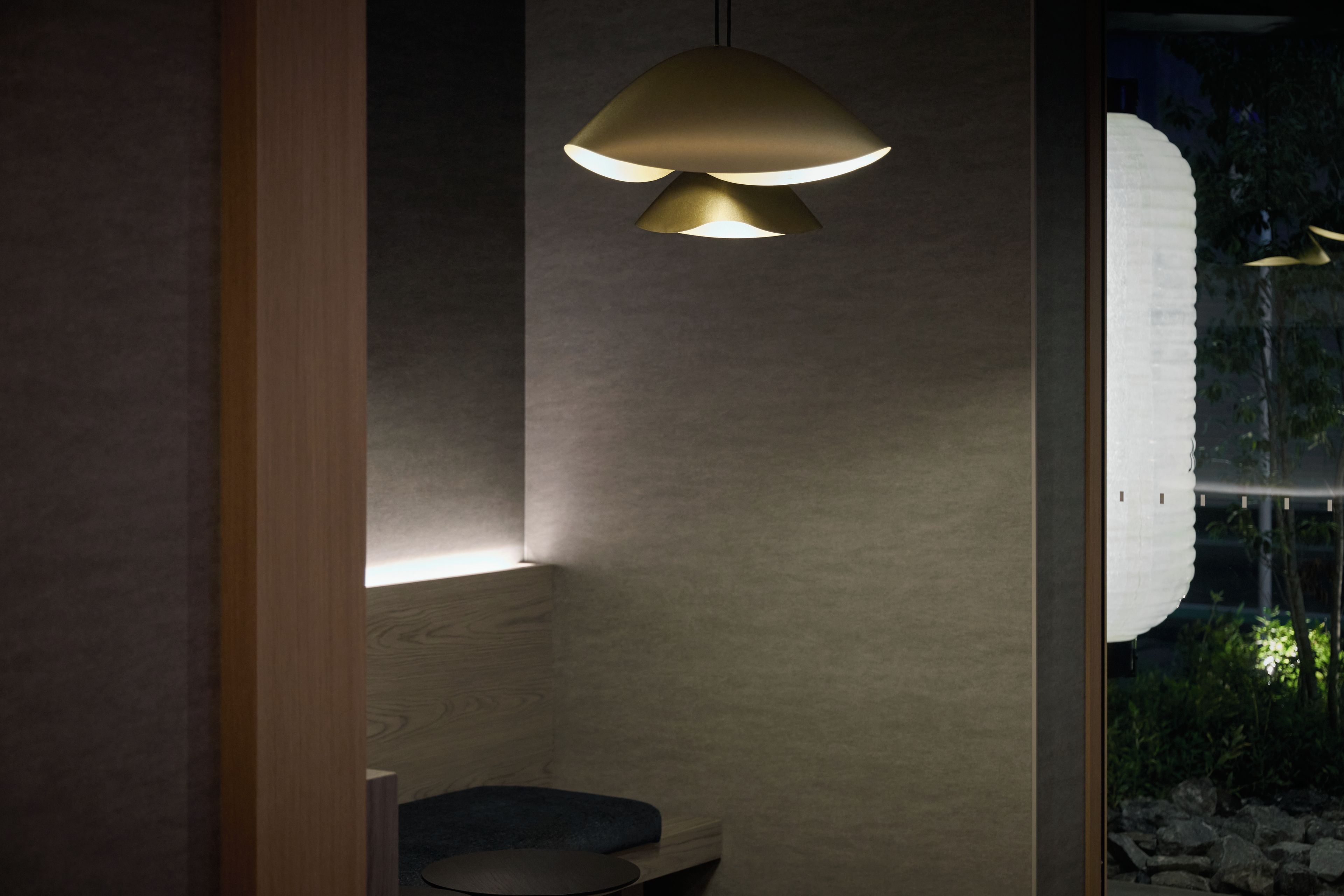 Un baño moderno con tocador de madera, un espejo redondo y una lámpara colgante.