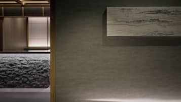 A room with a bed, a wall-mounted artwork, and a wooden floor.