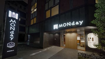 A building with a prominent 'MONDAY' sign, a modern design with dark and light brickwork, and a visible entrance.