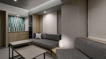 Um interior moderno com um sofá, uma mesa pequena e uma área de cozinha com micro-ondas.