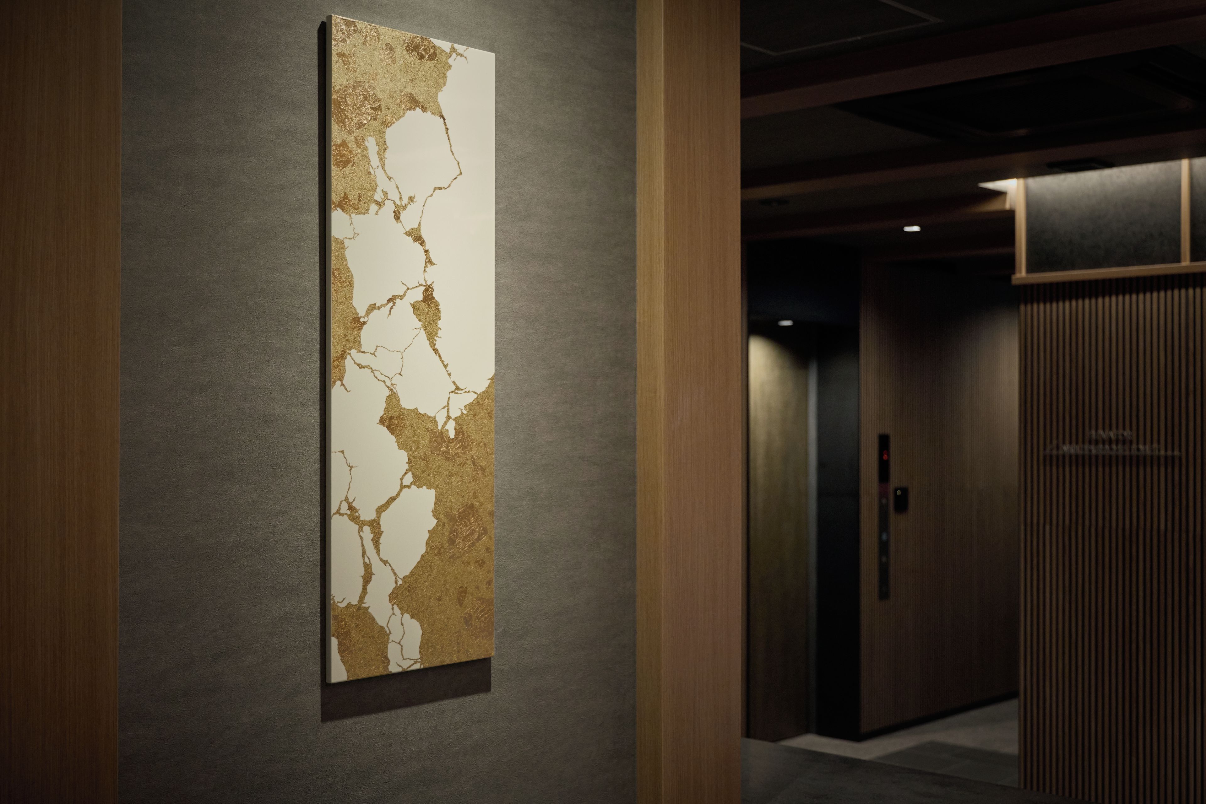 A hallway with a modern abstract painting on the wall and a wooden door at the end.