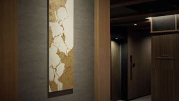 Un passadís amb un quadre abstracte modern a la paret i una porta de fusta al final.