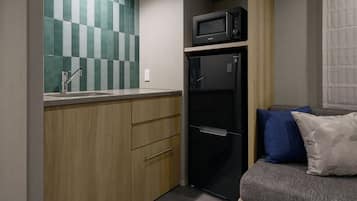 Une petite cuisine équipée comprenant un four à micro-ondes, un évier et des placards en bois.