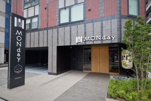 A modern building with a prominent 'MONday' sign, a black entrance with a glass door, and a 'PREMIUM' logo on a vertical sign. - Premium MONday ASAKUSA II (Tokyo)