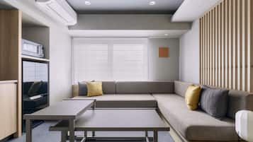 A modern living room with a sofa, a coffee table, and a built-in kitchen unit.