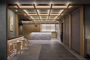 A modern interior with a bar area, seating, and a stone accent wall. - Premium MONday ASAKUSA II (Tokyo)