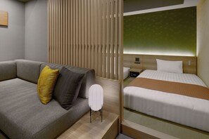 Una habitación de hotel con sofá, cama, mesita de noche y una pared con listones verticales.