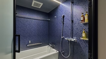 A bathroom with a bathtub, shower, and shelves with toiletries.