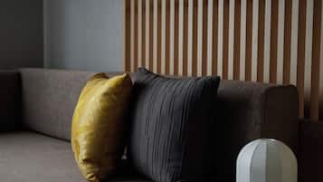 A sofa with two pillows, a white object, and a striped wall.