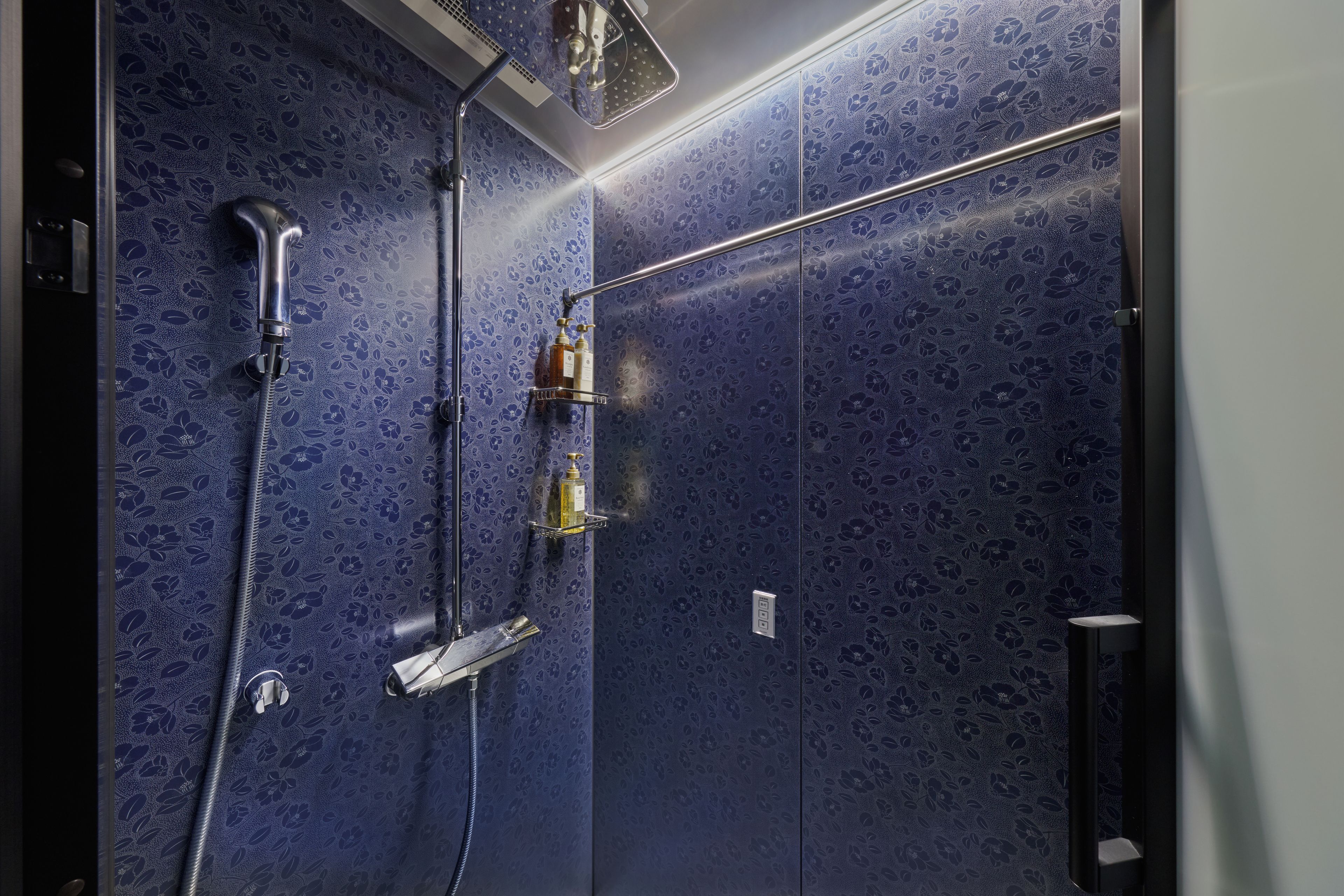 A bathroom with a shower, a towel rack, and a soap dispenser.