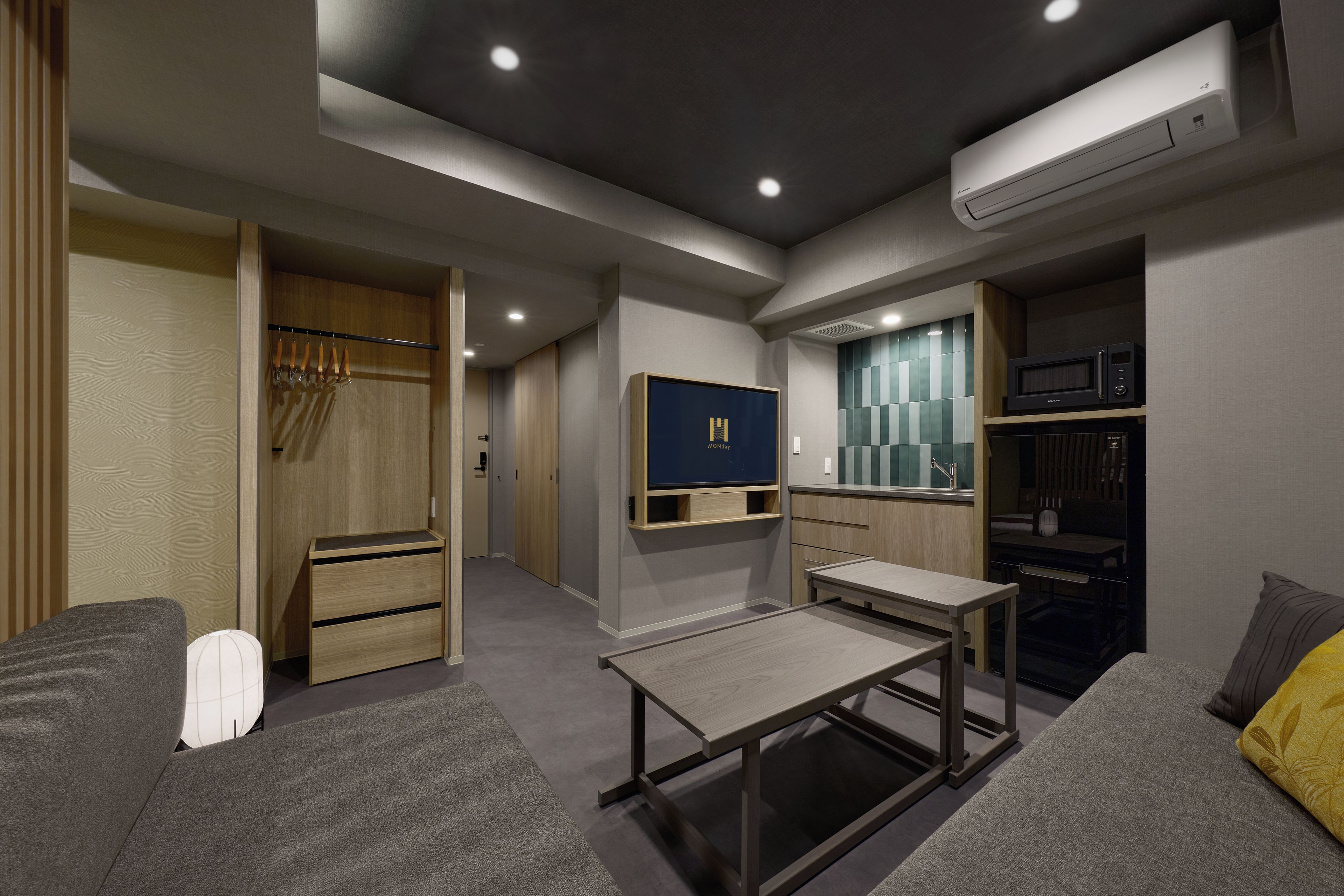A modern, well-lit room with a built-in TV, a microwave, and a small kitchenette.