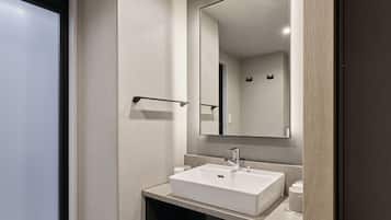 A modern bathroom with a white sink, a large mirror, and a towel rack.