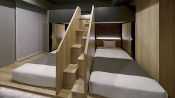 Una habitación pequeña con dos camas, una escalera de madera y una cortina gris.