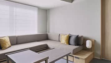 Un salon moderne avec un canapé d’angle, une petite table et un haut-parleur blanc.