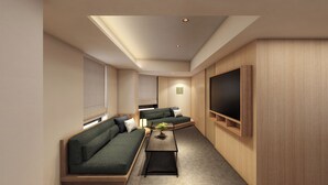 A modern living room with a sofa, a coffee table, and a flat-screen TV mounted on the wall.