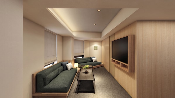 A modern living room with a sofa, a coffee table, and a flat-screen TV mounted on the wall.