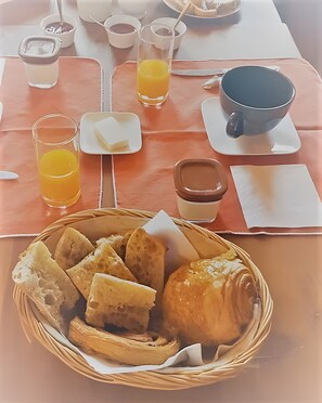 Ein Frühstückstisch mit Brot, Croissants und Orangensaft.