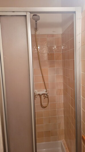 Eine Dusche mit Handbrause und am Wand montiertem Wasserhahn.