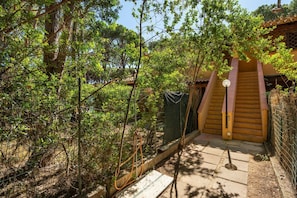 A wooden staircase leading to a building with a traditional design, surrounded by dense greenery. - Henry's House - 300mt from the sea (Santa Margherita di Pula)