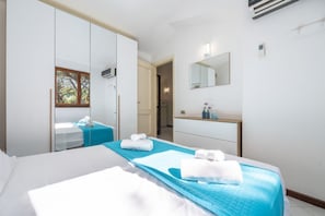 A hotel room with a bed, a wardrobe, a mirror, a dresser, and a bathroom visible through an open door. - Henry's House - 300mt from the sea (Santa Margherita di Pula)