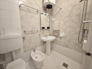 Ein modernes Badezimmer mit Toilette, Bidet, Waschbecken und Dusche.