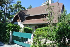 Ein Haus mit braunem Dach, einem grünen Tor und einem Verbotsschild für Parkplätze.