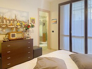 Une chambre à coucher avec un lit, une commode, une radio et un tableau.