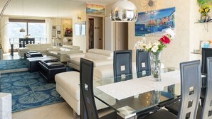A modern living room with a glass dining table, white sofas, and a large window. - Riflesso del Lario by Interhome (Bellano)