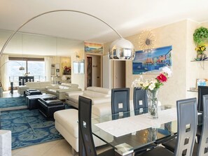 A modern living room with a glass dining table, white sofas, and a large window. - Riflesso del Lario by Interhome (Bellano)
