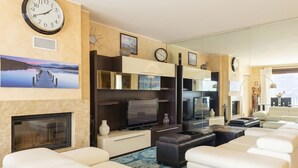 A modern living room with a fireplace, a large flat-screen TV, and a seating area with white sofas. - Riflesso del Lario by Interhome (Bellano)