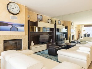 A modern living room with a fireplace, a large flat-screen TV, and a seating area with white sofas. - Riflesso del Lario by Interhome (Bellano)